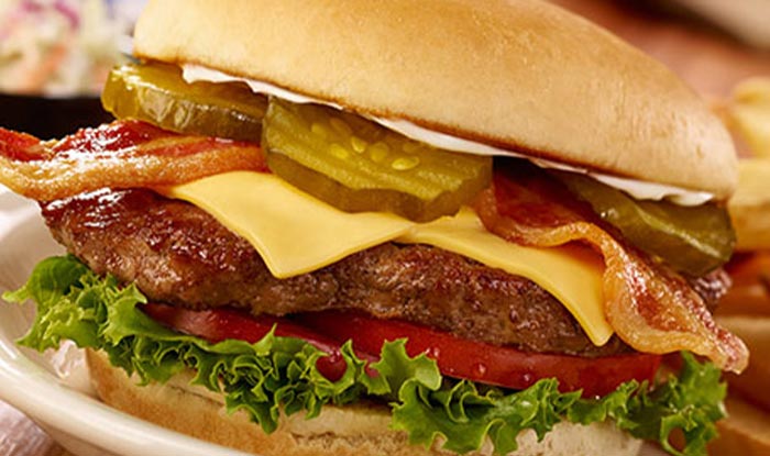 Close-up of a cheeseburger at Bricks & Ivy Tavern with bacon, pickles, lettuce, and tomato.