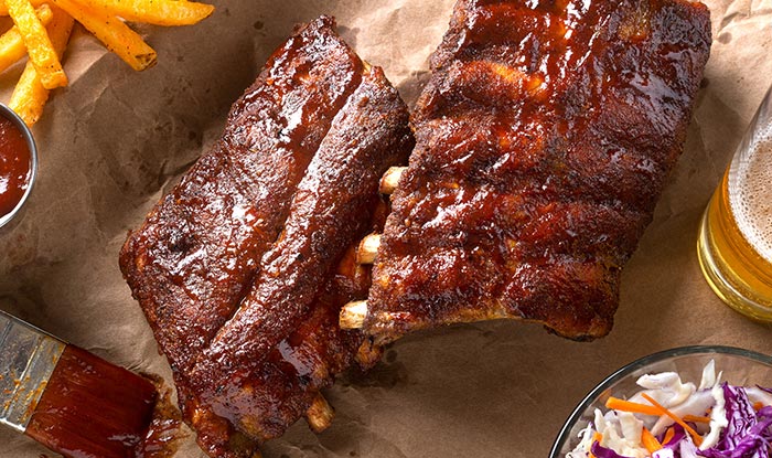 Barbecue ribs with sauce, fries, and coleslaw at Spring Grove Sports Bar, served with beer.