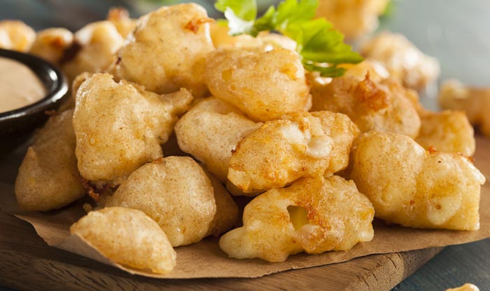 Golden fried cheese curds on parchment, garnished with parsley—classic sports bar food.