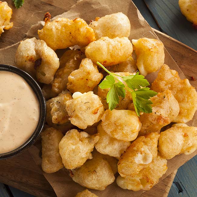 Golden fried cheese curds with dipping sauce, perfect for sharing at Bricks & Ivy Sports Bar.