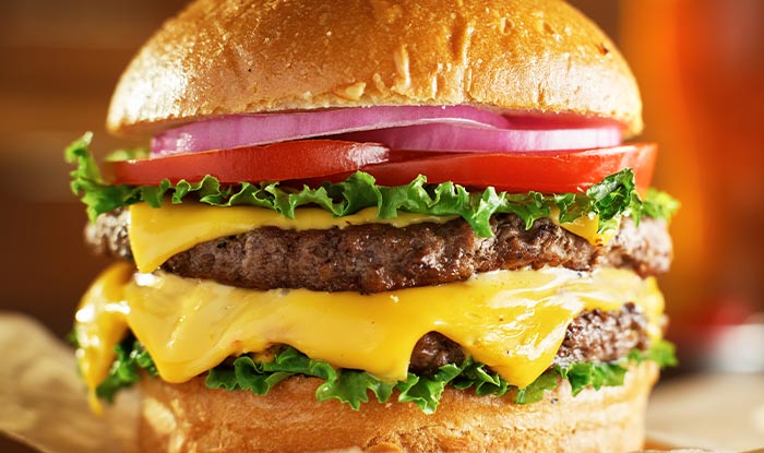 Close-up of a double cheeseburger at Bricks & Ivy Tavern with lettuce, tomato, and melted cheese.