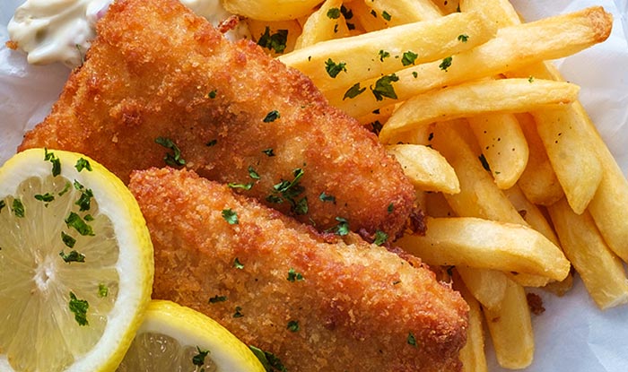 Crispy fried fish fillets with fries at Bricks & Ivy Sports Bar, served with tartar sauce and lemon.