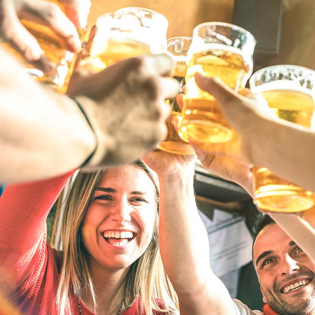 Group of people smiling and clinking beer glasses together at Bricks & Ivy Tavern.