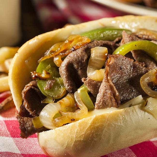 A Bricks & Ivy Philly cheesesteak with beef, onions, and peppers on a hoagie roll.