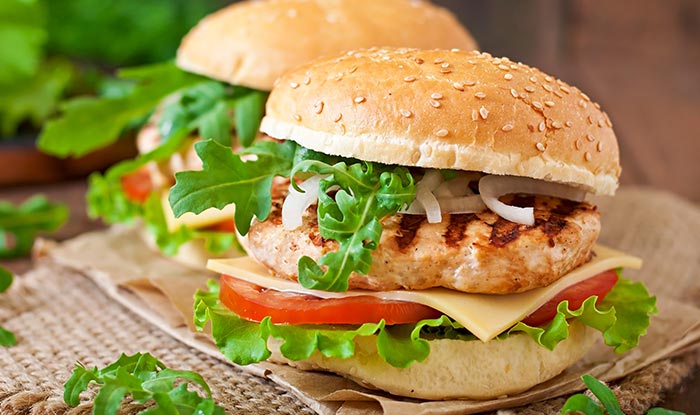 Grilled chicken burgers with cheese, lettuce, and arugula on sesame buns at Bricks & Ivy.