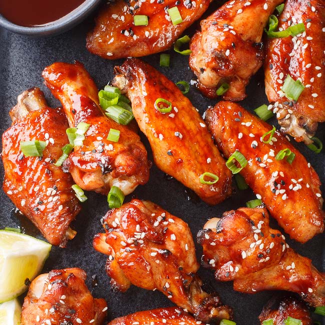 Bricks & Ivy restaurant's chicken wings glazed with sauce, sesame seeds, and lemon wedges.